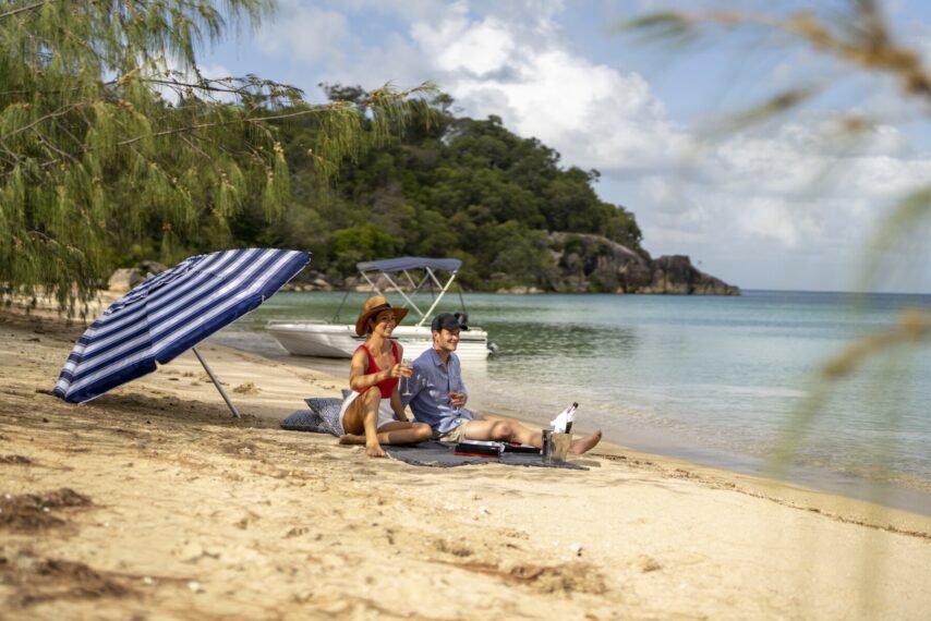 Couple enjoying a picnic on a secluded beach, during their Dinghy Adventure